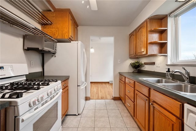 kitchen featuring dishwashing machine, sink, light tile patterned floors, a wealth of natural light, and white range with gas cooktop