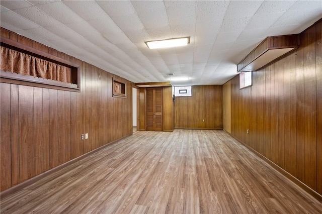 basement featuring wooden walls and light hardwood / wood-style floors