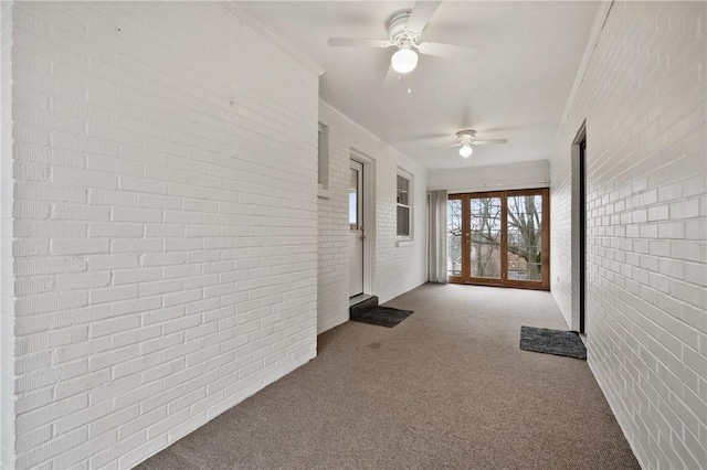 hall featuring light carpet, crown molding, and brick wall