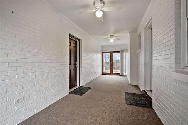 hallway with crown molding, brick wall, carpet floors, and french doors