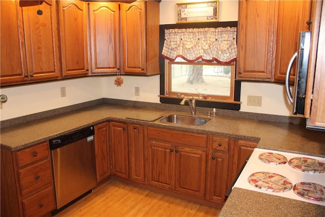 kitchen with appliances with stainless steel finishes, sink, and light hardwood / wood-style flooring