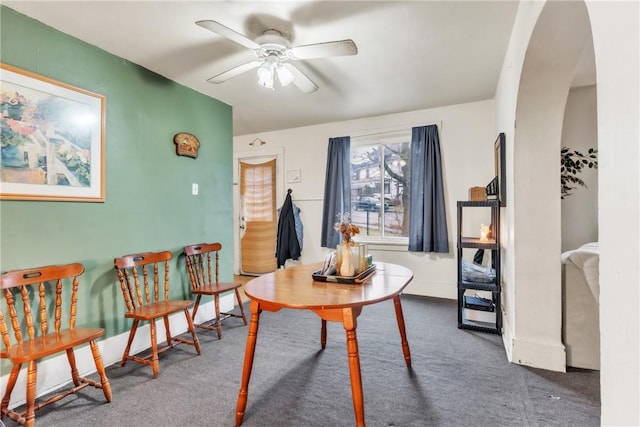 dining space with ceiling fan and dark colored carpet