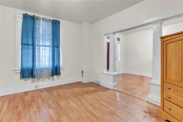 unfurnished room featuring hardwood / wood-style floors, a healthy amount of sunlight, and ornate columns