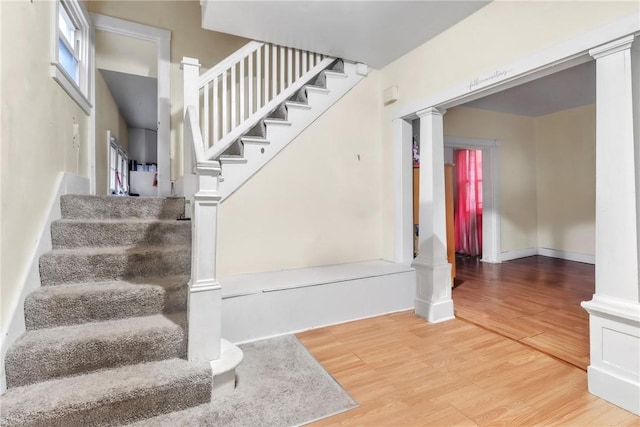 stairs featuring hardwood / wood-style flooring and decorative columns