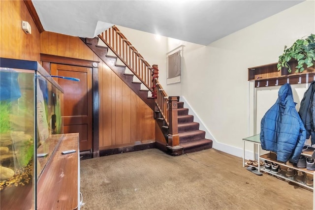 stairs with carpet and wood walls