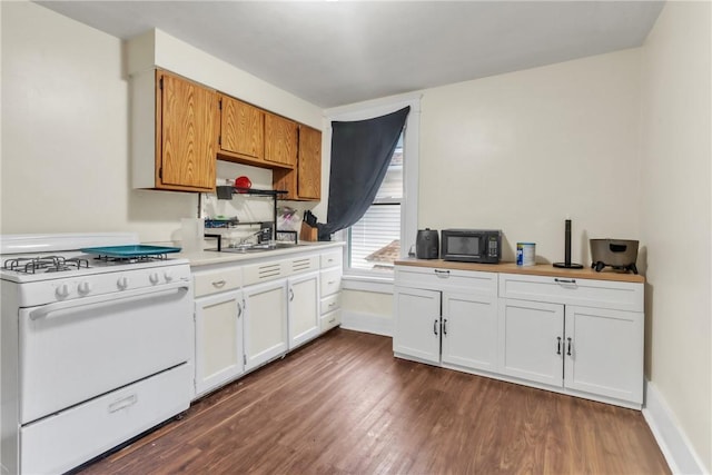 kitchen featuring white range with gas cooktop, dark wood-type flooring, and white cabinets