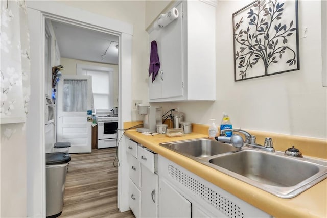 kitchen featuring white range oven, sink, white cabinets, and light hardwood / wood-style flooring