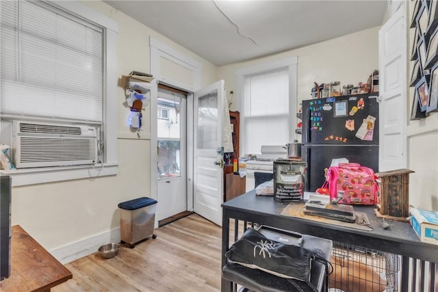 kitchen with black refrigerator, cooling unit, white cabinets, and light wood-type flooring