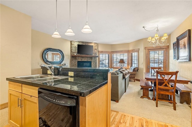 kitchen with a kitchen island with sink, sink, a fireplace, and dishwasher