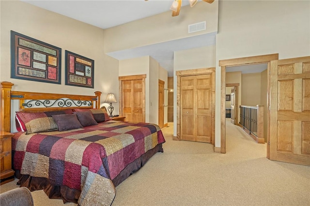 bedroom featuring a towering ceiling, ensuite bathroom, ceiling fan, and carpet