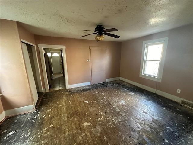 unfurnished bedroom with ceiling fan, dark hardwood / wood-style flooring, and a textured ceiling