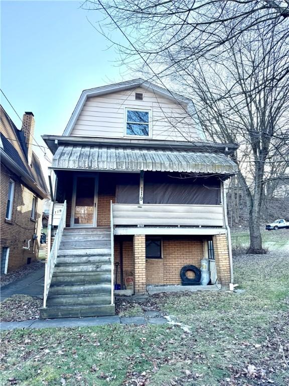 view of front of property featuring brick siding, a gambrel roof, covered porch, and stairs