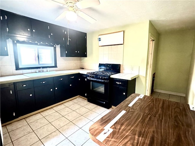 kitchen featuring sink, light tile patterned floors, ceiling fan, black gas range, and decorative backsplash