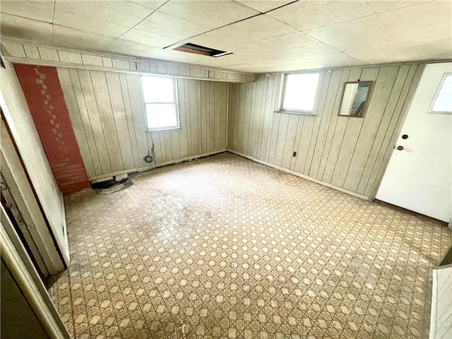 below grade area with baseboards, wood walls, and a healthy amount of sunlight