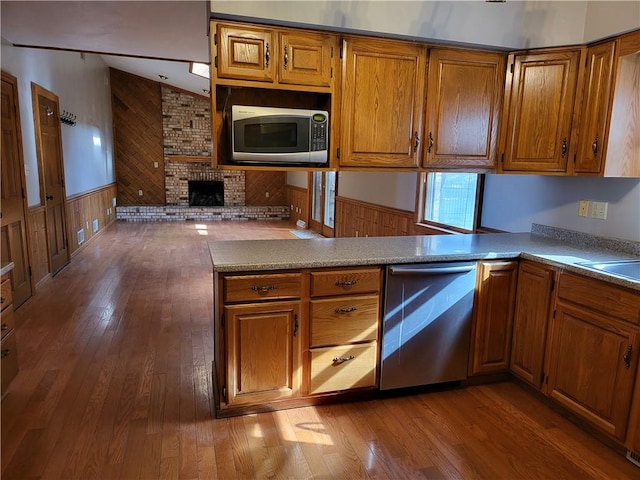 kitchen with hardwood / wood-style flooring, a fireplace, stainless steel appliances, and kitchen peninsula