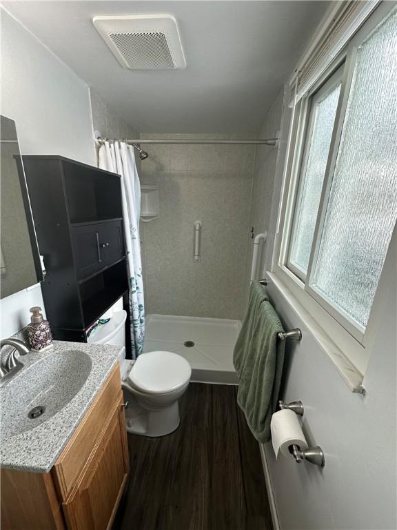 bathroom with hardwood / wood-style flooring, vanity, a wealth of natural light, and toilet