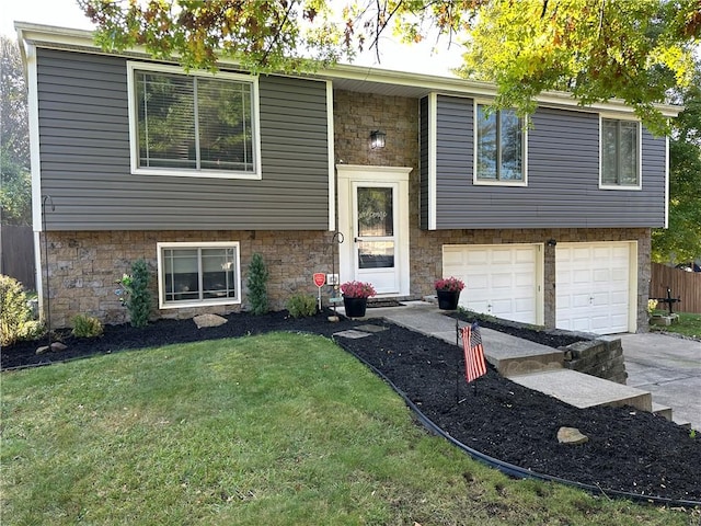 raised ranch featuring a garage and a front lawn