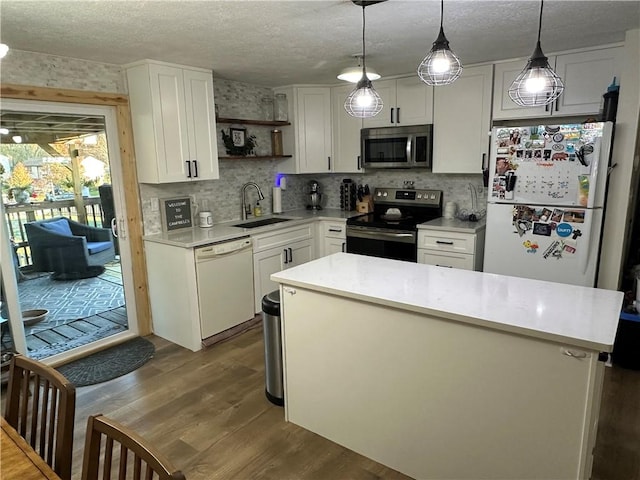 kitchen with sink, white cabinetry, a kitchen island, pendant lighting, and stainless steel appliances