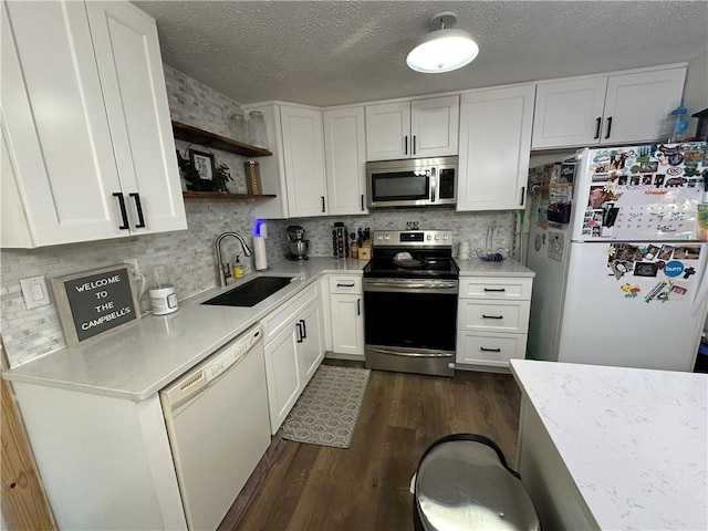 kitchen with dark wood-type flooring, sink, a textured ceiling, stainless steel appliances, and white cabinets