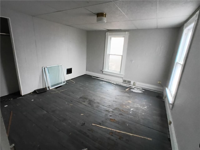 spare room with dark hardwood / wood-style floors and a drop ceiling