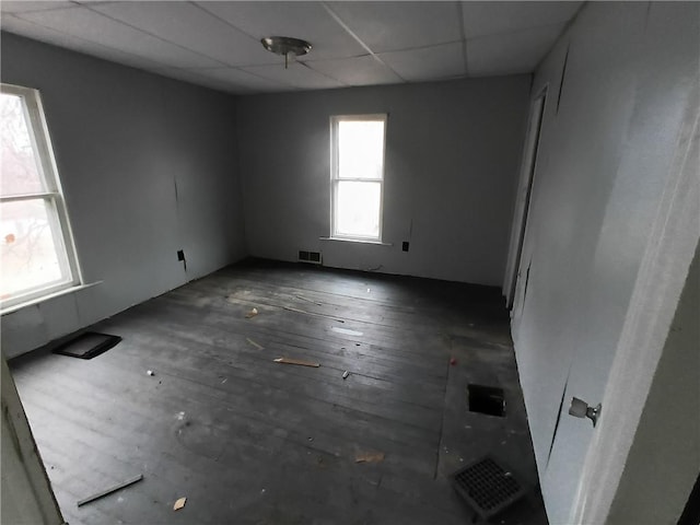 spare room featuring a paneled ceiling and dark hardwood / wood-style floors