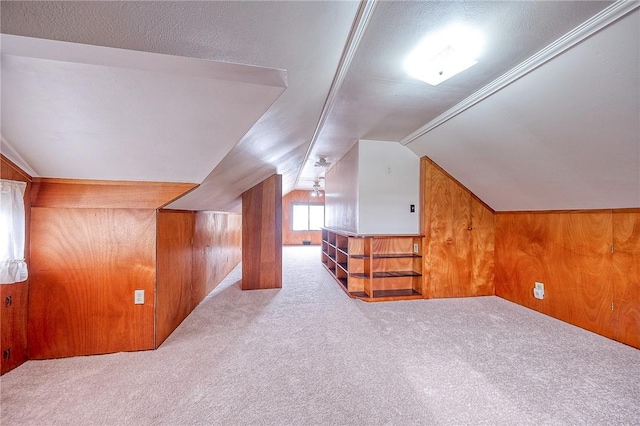 bonus room with light colored carpet, lofted ceiling, and wood walls