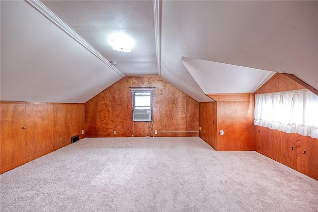 additional living space featuring vaulted ceiling, carpet, and wooden walls