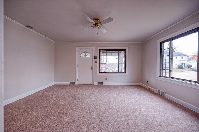 carpeted foyer entrance with ornamental molding and ceiling fan