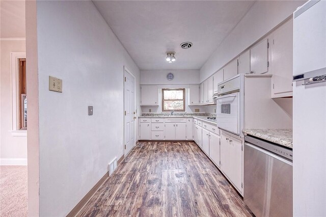 kitchen with dark hardwood / wood-style flooring, dishwasher, sink, and white cabinets