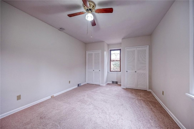 unfurnished bedroom featuring multiple closets, ceiling fan, and carpet floors