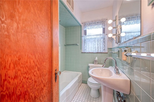 bathroom featuring a bath, tile patterned flooring, tile walls, and toilet