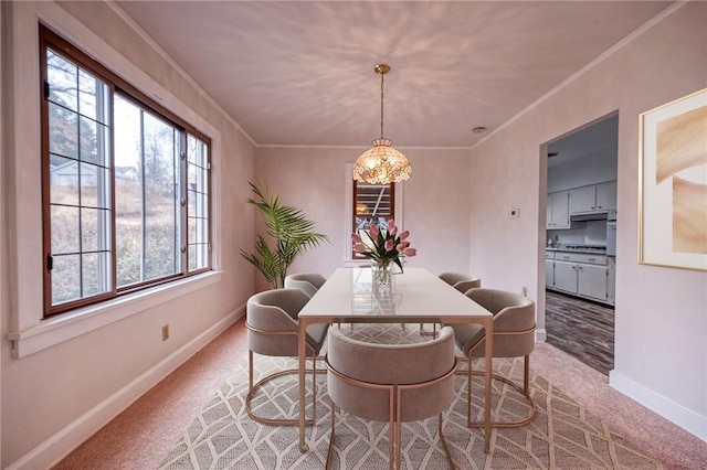 dining space featuring ornamental molding, carpet flooring, and a notable chandelier