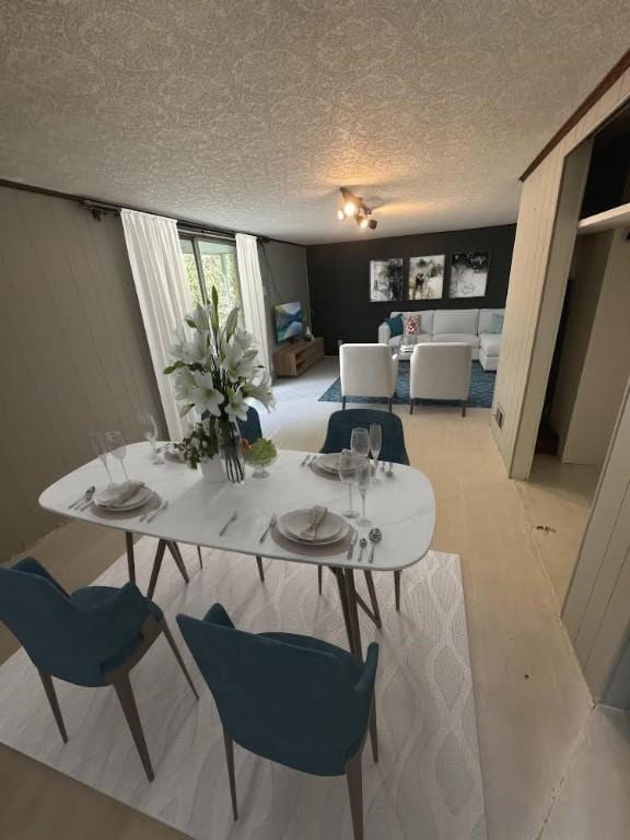 dining room with a textured ceiling and wood walls