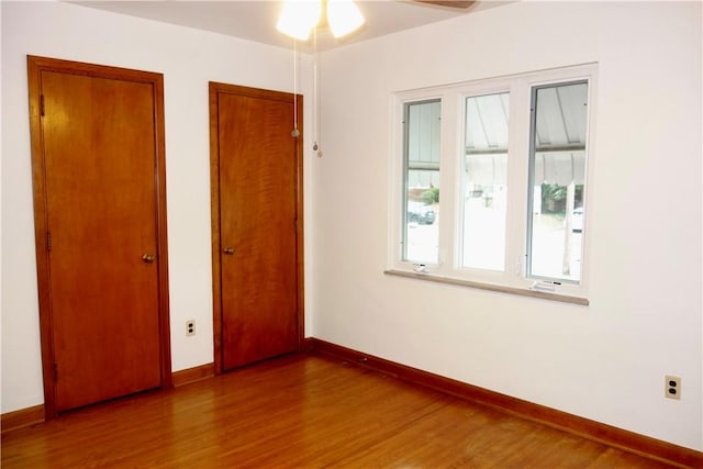 unfurnished bedroom with wood-type flooring and multiple closets