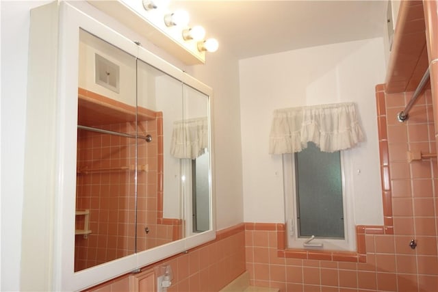 bathroom featuring a tile shower and tile walls