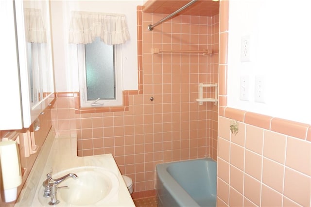 full bathroom featuring tiled shower / bath combo, sink, tile walls, and toilet