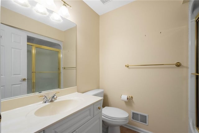 bathroom with vanity, a shower with door, and toilet