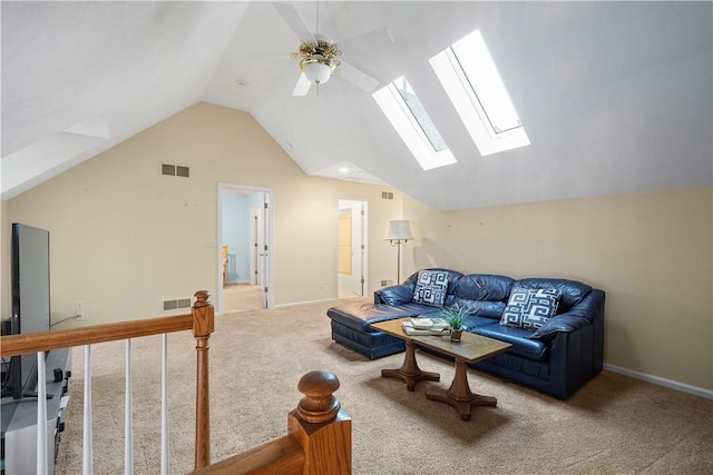 carpeted living room with ceiling fan and vaulted ceiling with skylight