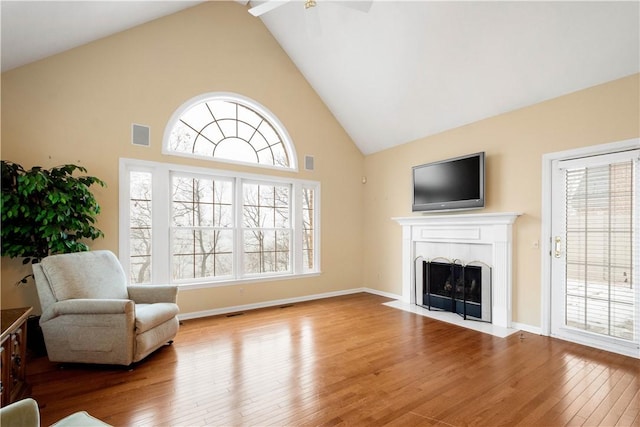 living area featuring a healthy amount of sunlight, wood-type flooring, and high vaulted ceiling