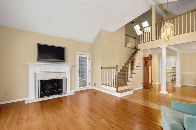 unfurnished living room with wood-type flooring, high vaulted ceiling, and ornate columns