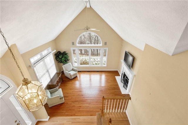 living room featuring ceiling fan, high vaulted ceiling, and light wood-type flooring