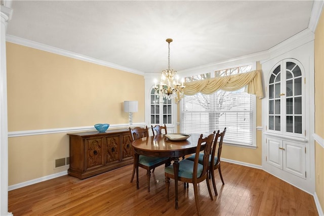 dining room featuring hardwood / wood-style flooring, ornamental molding, and an inviting chandelier