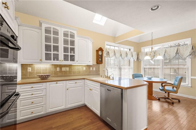 kitchen featuring stainless steel dishwasher, white cabinets, and kitchen peninsula