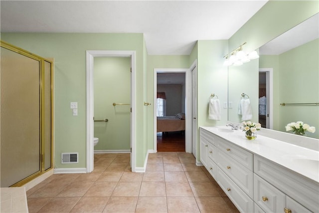 bathroom with tile patterned flooring, vanity, toilet, and a shower with shower door