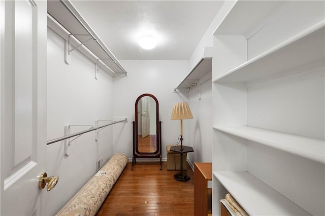 walk in closet with dark wood-type flooring