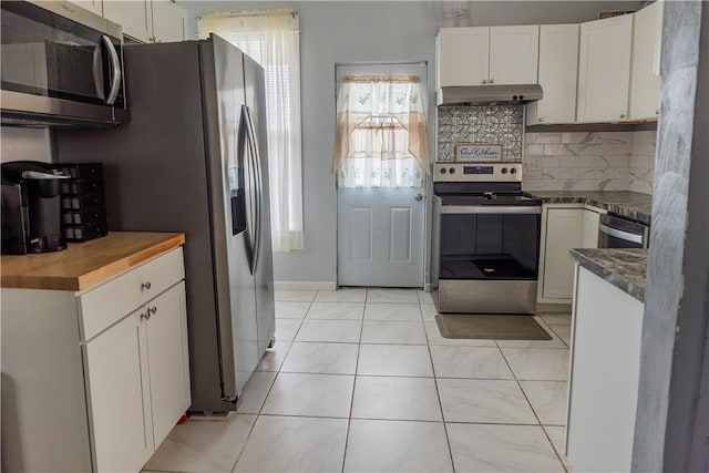 kitchen featuring tasteful backsplash, stainless steel appliances, light tile patterned flooring, and white cabinets