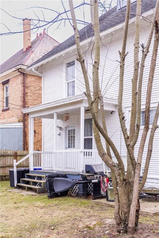 rear view of property featuring a yard and a porch