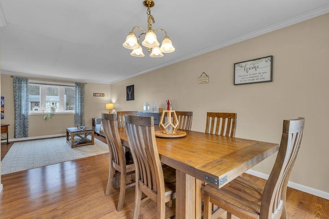 dining space with a notable chandelier, ornamental molding, and light hardwood / wood-style floors