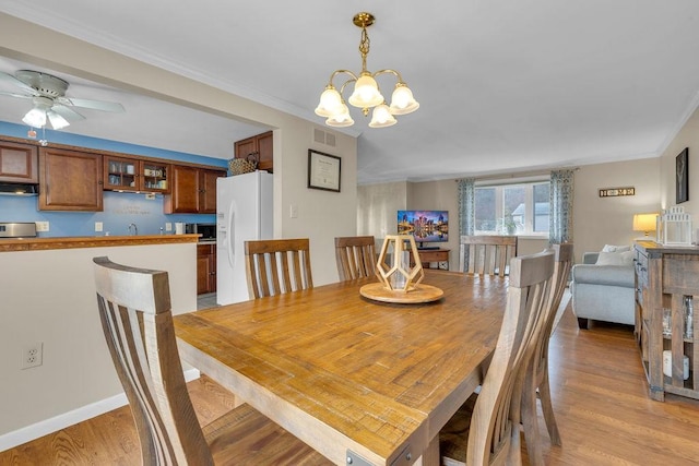 dining area with crown molding, ceiling fan with notable chandelier, and light hardwood / wood-style flooring