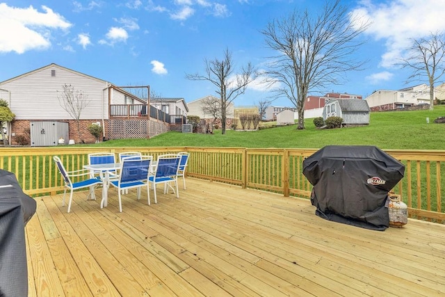 wooden deck featuring a grill, a yard, and a storage unit